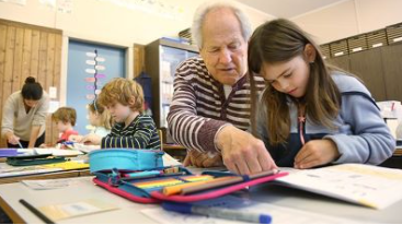 Senior und Schulkind beim Lesen am Pult im Schulzimmer, Bild zVg. 