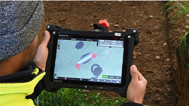 Archäologe hält Tablet und untersucht die Fundstelle mit einem speziellen Tool. Bild zVg.