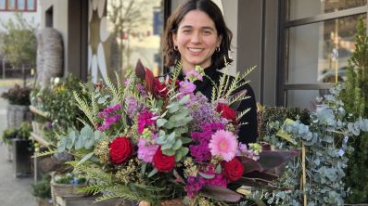 Junge Frau vom Beruf Floristik hält einen grossen, bunten Blumenstrauss in den Farben Grün, Pink und Rot., Bild: zVg. 